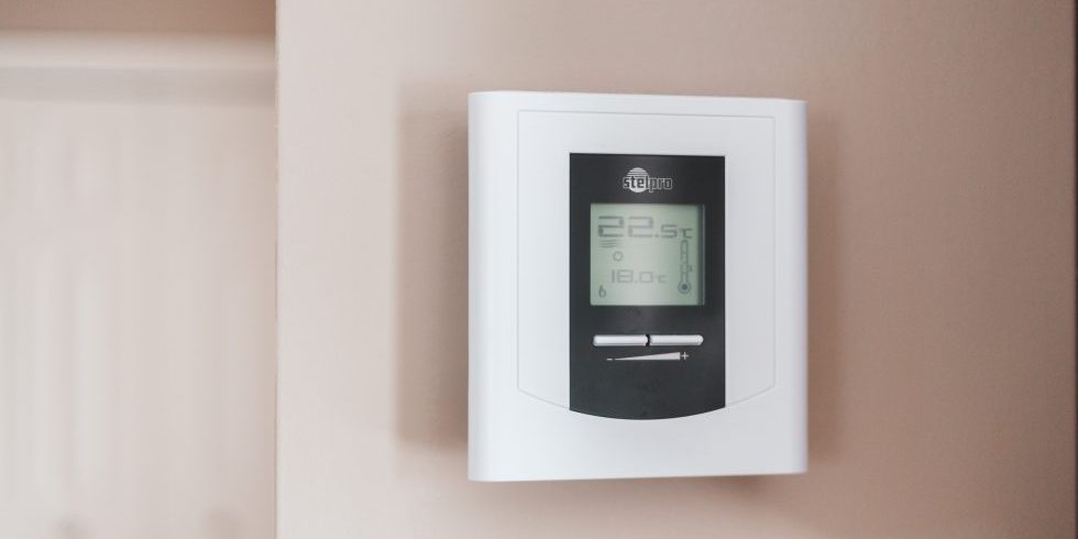 Digital thermostat an einer Wand montiert mit Temperatureinstellung und Anzeige.